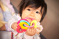 Enfant holding a teething rings shaped like an apple at Masci & Hale Advanced Aesthetic and Restorative Dentistry